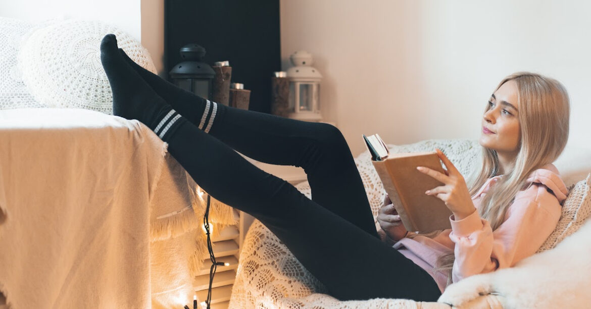 Comment recréer un décor style hygge dans votre salon - une jeune femme lit dans son coin hyggekrog