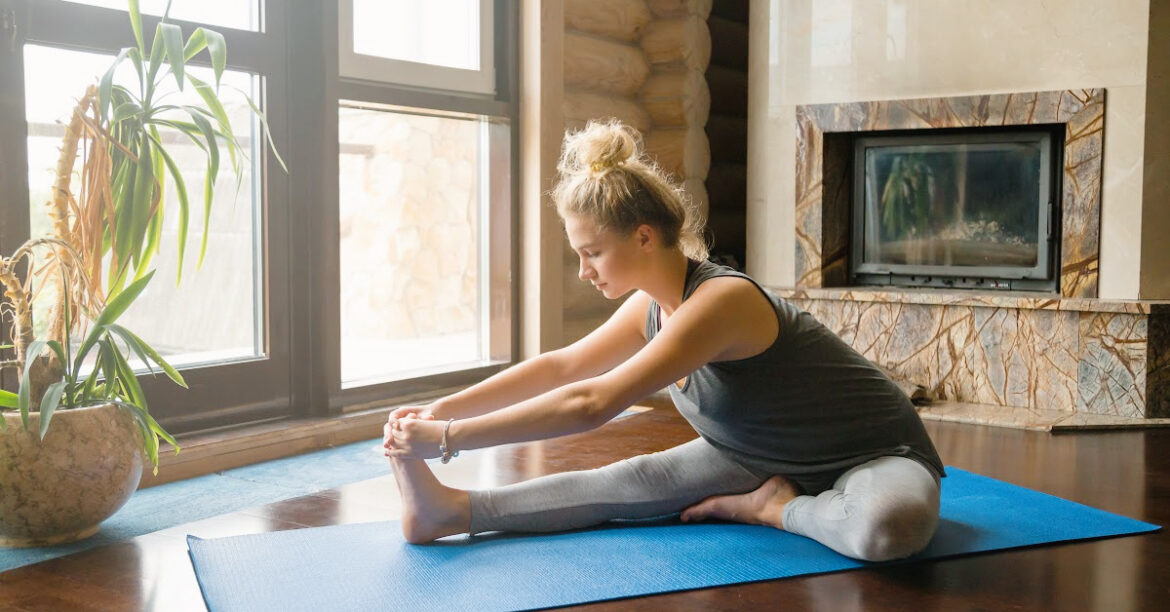 20 Activités Chaleureuses Près du foyer pour le Plaisir et la Détente en Hiver - une jeune femme fait du yoga au coin du foyer