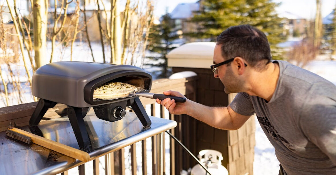 Un homme est en train de faire cuire une pizza dans le four à pizza Pizzero® par Ambiance®