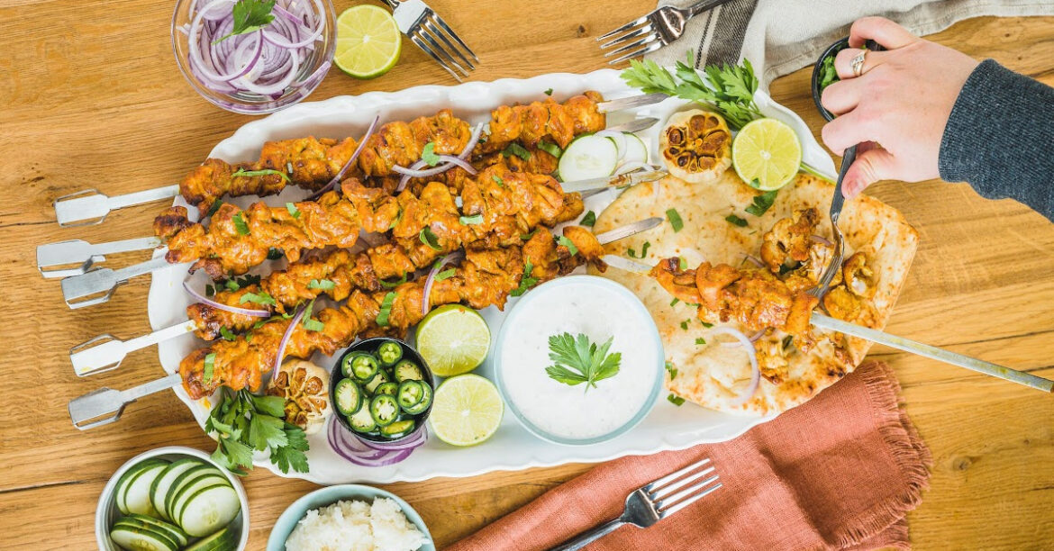 Une assiette de brochettes de poulet avec un pain naan