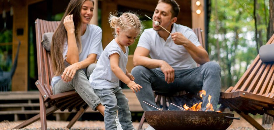 Un couple avce un enfant mange des guimauves aupres d'un feu de camp